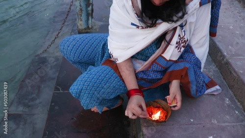 young girl devotee lighting oil lamps to offer holy river ganges at evening from top angle photo