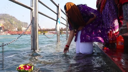 young girl devotee offering flower pot to holy river ganges at morning from flat angle photo