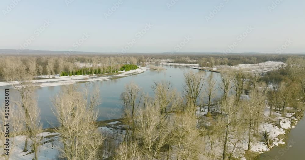 Flooded river floodplain with snow field and forest in wild lanscape. High altitude wide drone view flooded area at spring time cloudy day Flooded river floodplain with snow field and forest in wild lanscape. High altitude wide drone view flooded area at spring time cloudy day