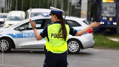 Policjantka ruchu drogowego kieruje ruchem ma skrzyżowaniu dróg w mieście. 