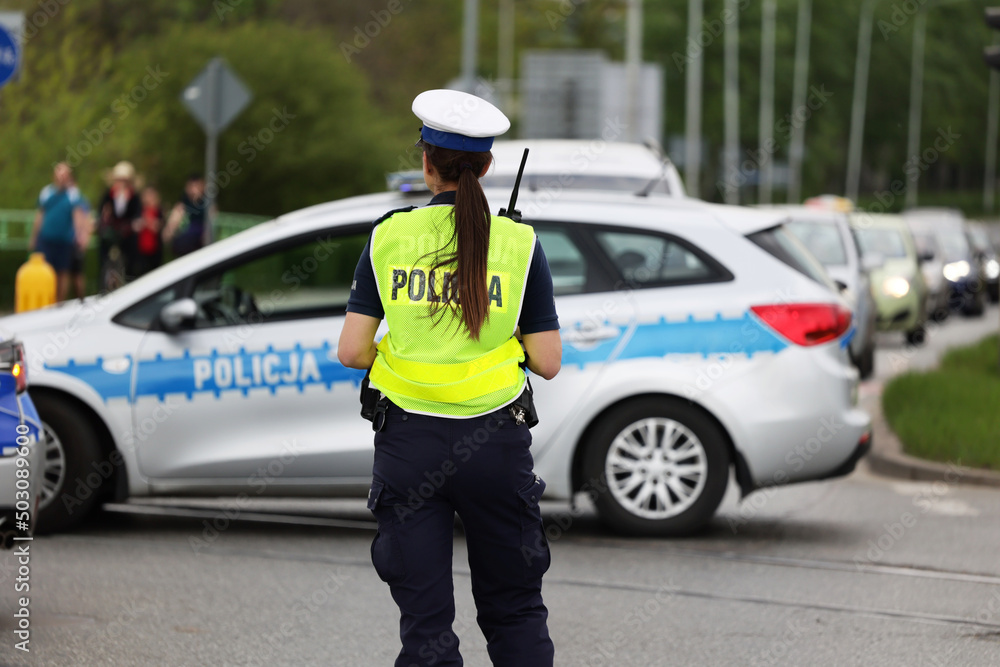 Policjantka ruchu drogowego kieruje ruchem ma skrzyżowaniu dróg w mieście.  - obrazy, fototapety, plakaty 