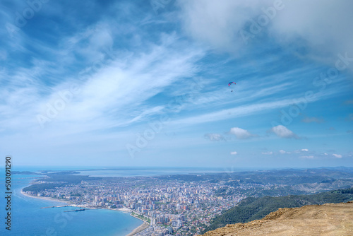 Athlete paragliding against the backdrop of a cloudy sky over the city on a summer day. Albania