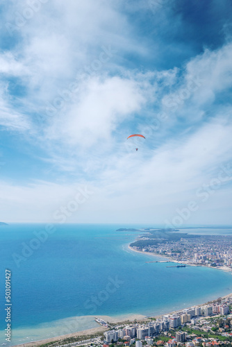 Athlete paragliding against the backdrop of a cloudy sky over the city on a summer day. Albania