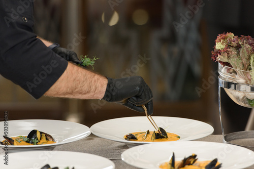 chef prepares carrot cream soup with seafood in a restaurant