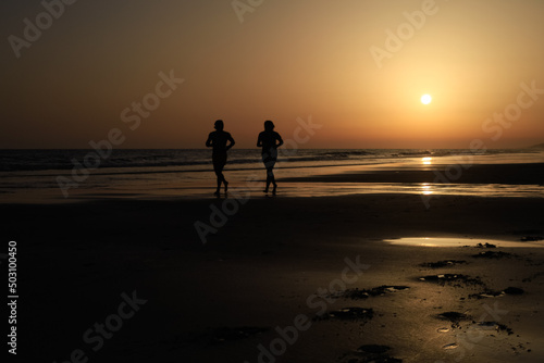 long shot of two runners on a great spanish beach at sunset