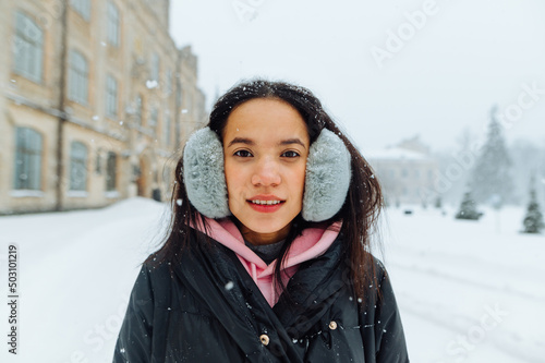 Winter portrait portrait of attractive woman in warm clothes in snowfall on a walk on a background of snowy beautiful landscape. photo