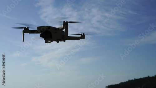 Flying drone in the air against the background of a blue sky with a slight cloudiness. High quality 4k footage