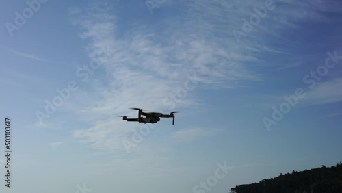 Flying drone in the air against the background of a blue sky with a slight cloudiness. High quality 4k footage
