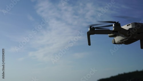 Flying drone in the air against the background of a blue sky with a slight cloudiness. High quality 4k footage