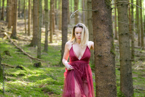 Sexy woman wearing magenta dress in forest.