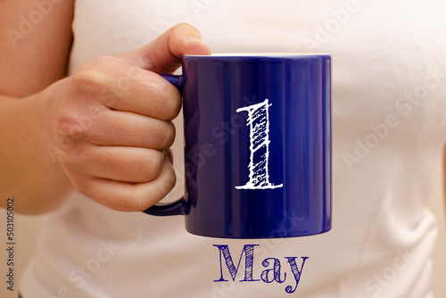 The inscription on the blue cup 1 may. Cup in female hand, business concept