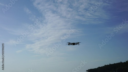 Flying drone in the air against the background of a blue sky with a slight cloudiness. High quality 4k footage