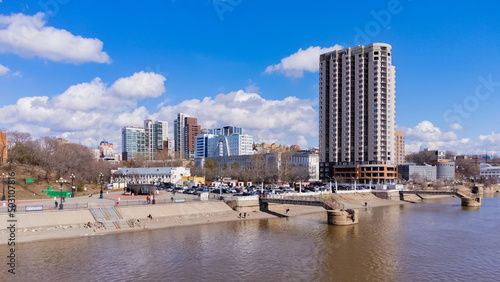 City embankment on the Amur River in Khabarovsk in early spring. A sunny day. The ice on the river has already melted. The trees haven't turned green yet. People are walking along the embankment.  © MASTERVIDEOSHAR