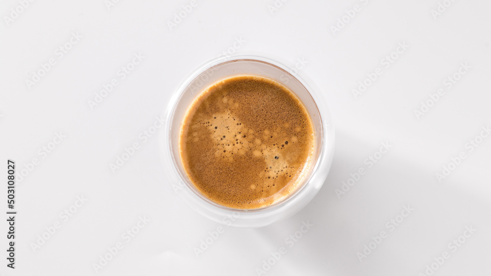 Freshly brewed coffee in a glass cup on a white background, top view, central composition Freshly brewed coffee in a glass cup on a white background, top view, central composition