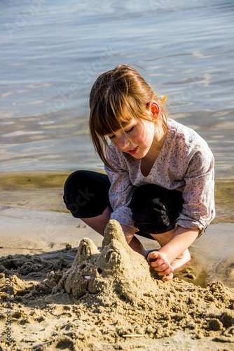 a little girl makes a sand sculture of cat