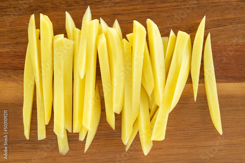 raw sliced potatoes on on wooeden cutting board background. photo