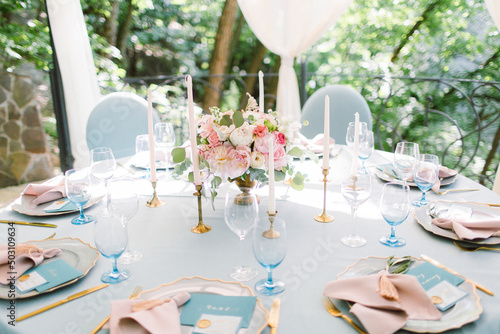 Wedding decor in blue. Banquet tables decorated bouquet with peonies on the tables are pink plates, glasses and candles