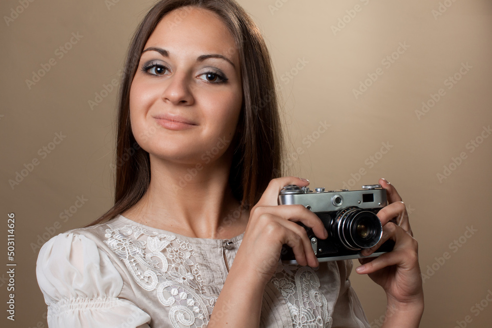 Young brown haired woman in beautiful dress holding retro camera Young brown haired woman in beautiful dress holding retro camera