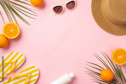 Summer holidays concept. Top view photo of sunhat sunglasses striped yellow slippers sunscreen bottle juicy oranges and palm leaves on isolated pastel pink background with copyspace in the middle