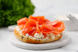 Bagel sandwich with salmon and cream cheese on marble board and white background