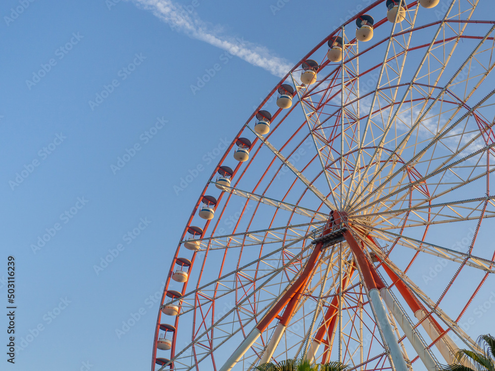 Ferris wheel against the sky. Amusement park on the sea. Rest zone.