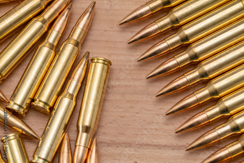 A row of cartridges with 7.62 caliber bullets for a Kalashnikov assault rifle on a textured background, close-up, selective focusing. Concept: sale of weapons under lend-lease, assistance with weapons