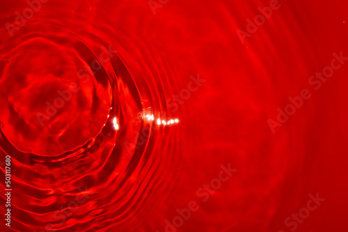 calm red water and a drop that made rings in the left corner of the abstract water background, romantic summer design