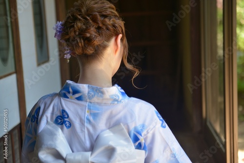 縁側でたたずむ浴衣を着た若い女性の後ろ姿
