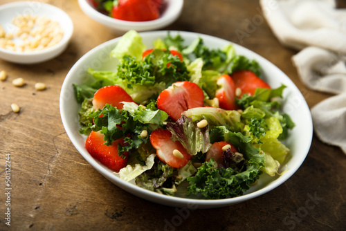 Healthy green salad with strawberry and pine nuts