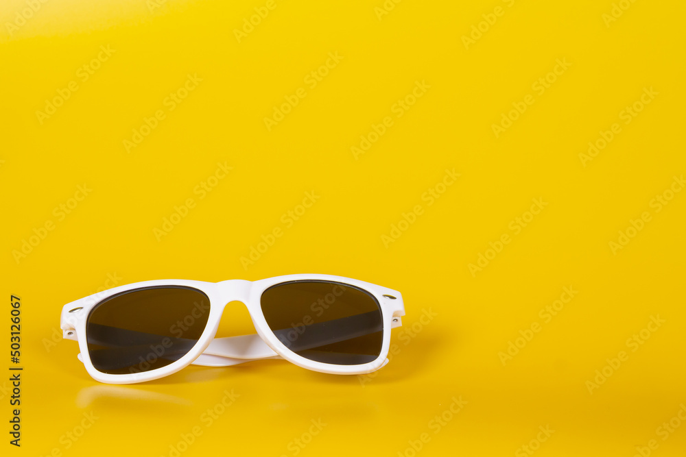 White sunglasses on a yellow background. Hello summer and sunshine White sunglasses on a yellow background. Hello summer and sunshine