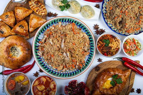 The concept of oriental cuisine. Assorted Uzbek food set, pilaf, samsa, lagman, manta, shurpa central asia food. Homemade Uzbek pilaf or plov from lamb served in cast iron cookware