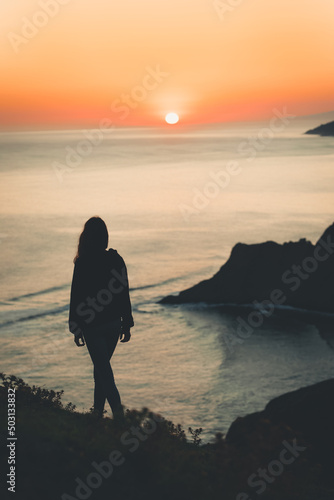 Canvas Print Vertical shot of a silhouette of a woman holding a surfing board