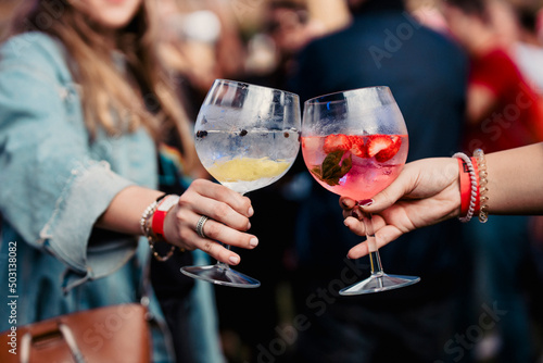 Two women holding a gin and tonic and toasting during a music festival photo