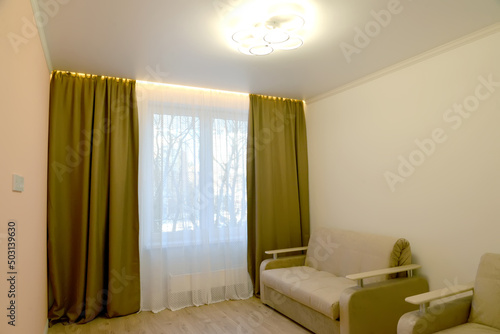 A fragment of the interior of a living room with a ceiling lamp and LED window lighting