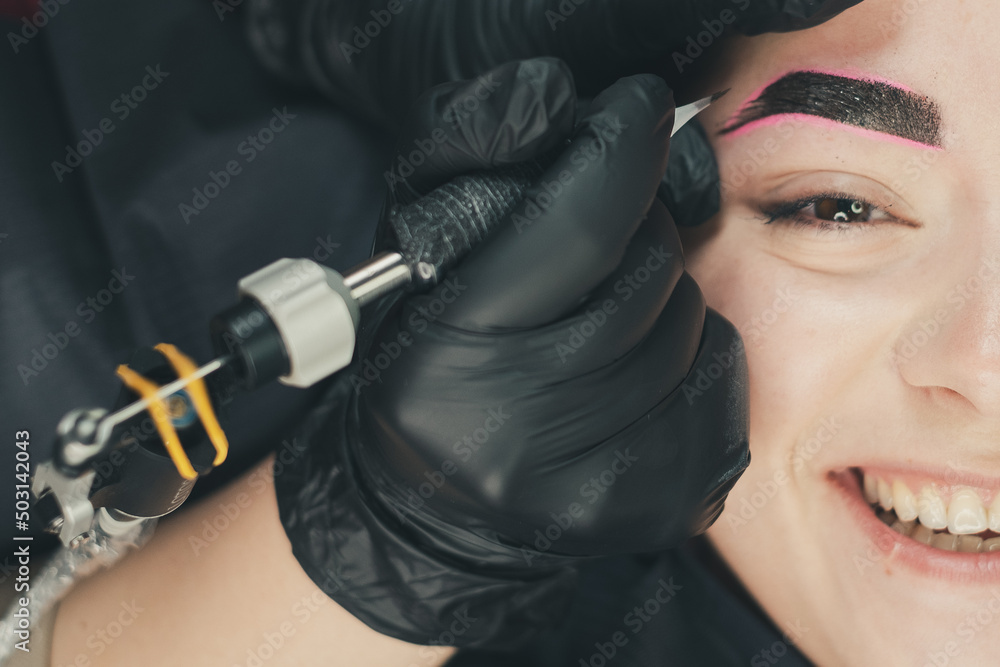 The master of permanent make up performs eyebrow microblading in beauty salon