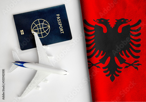Flag of Albania with passport and toy airplane. Flight travel concept 