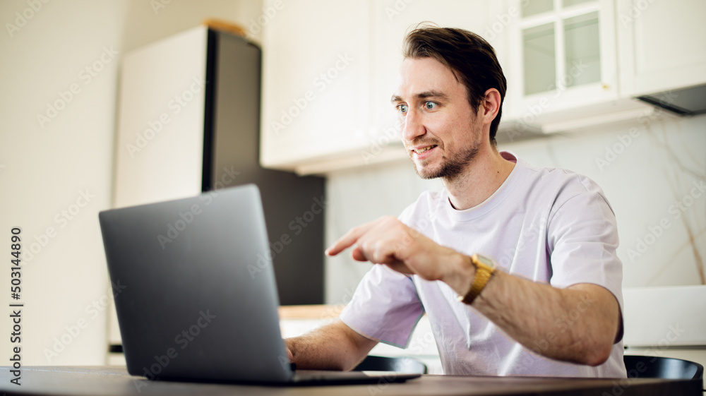 Man at laptop at home workplace chooses the point of destination for trip or working at home, studding on online courses with internet. 