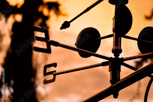 Beautiful silhouette of a weather vane during sunset on the orange sky background