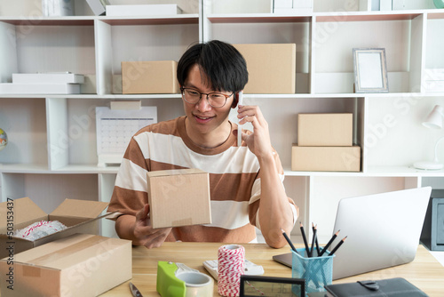 Online shopping concept a retailer holding a parcel post while talking with his customer on the mobile phone.