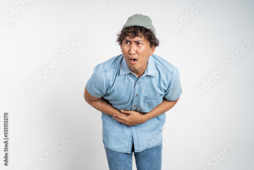 asian young man having stomach ache on background isolated. starving and hungry concept