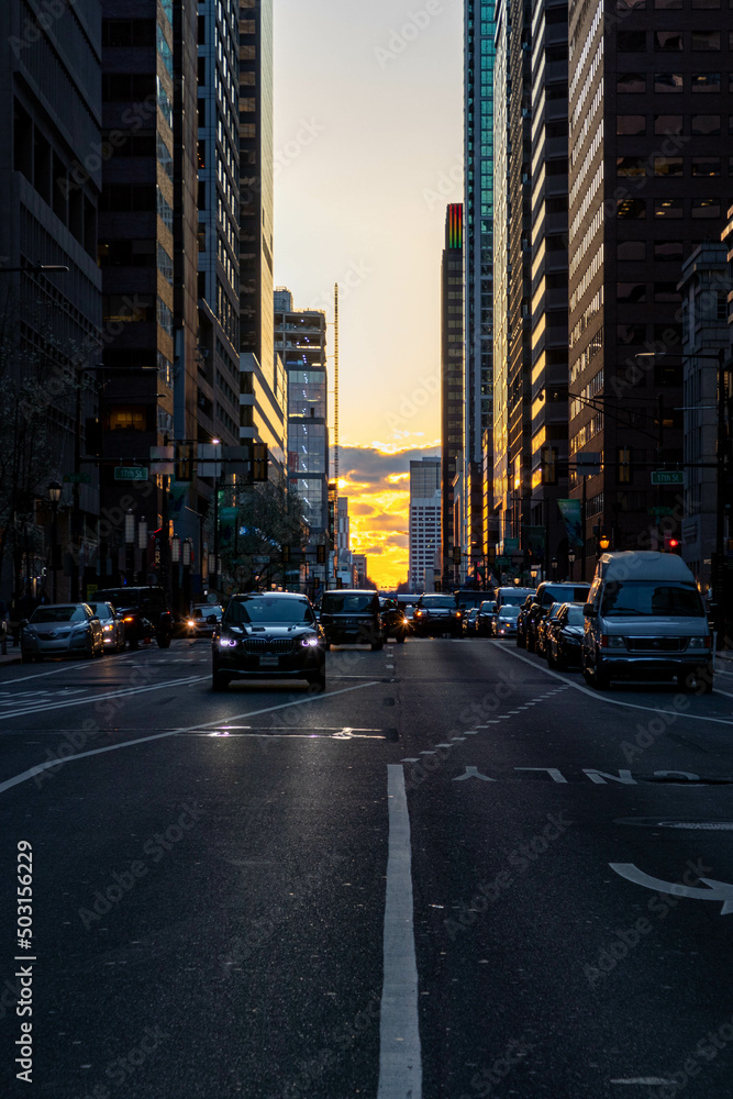 Naklejka premium Cars Driving at Sunset by Buildings in Philadelphia