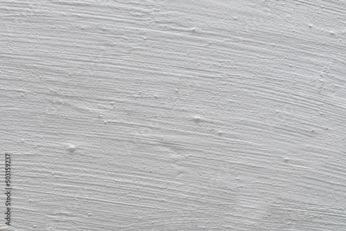 The tecture of a plastered wall whitewashed with a fringe. Gray background. Fragment of a gray wall with rough strokes of whitewash.
