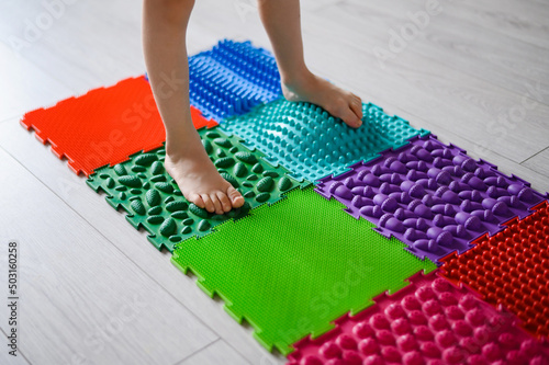 The child walks on a massage orthopedic foot mat. Prevention of flat feet