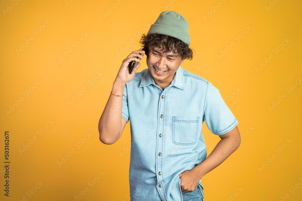 portrait of asian young man laughing while making phone call on isolated background portrait of asian young man laughing while making phone call on isolated background