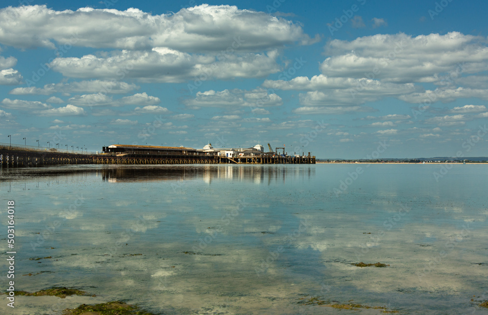 Reflections: clouds and pier at low tide