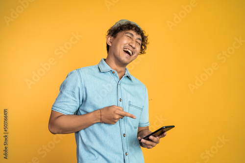 young man laugh hard when looking at a mobile phone on isolated background
