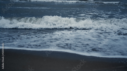 Waves foam splash beach in sea background landscape. Blue ocean water surface.