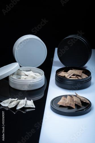 Closeup of two Swedish smokeless tobacco products. Snus cans with white and regular portion snuff