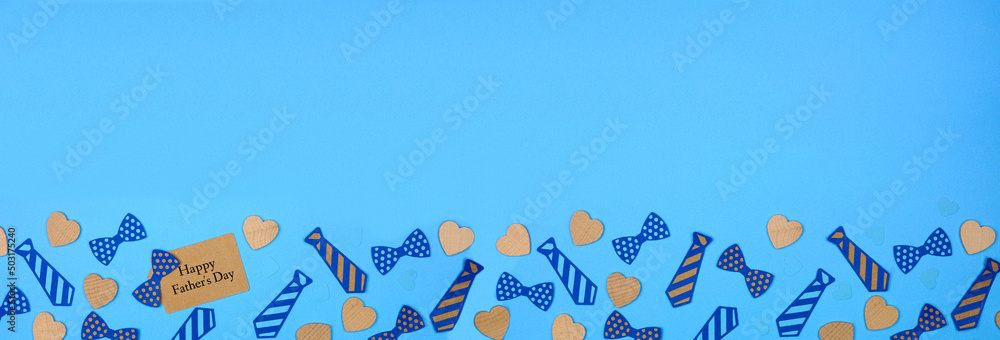 Happy Fathers Day gift tag with bottom border of paper tie decorations and wood hearts on a blue paper banner background. Top down view with copy space. - obrazy, fototapety, plakaty 
