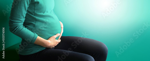 Young pregnant woman holds her hands on her swollen belly. Love concept. Horizontal with copy space